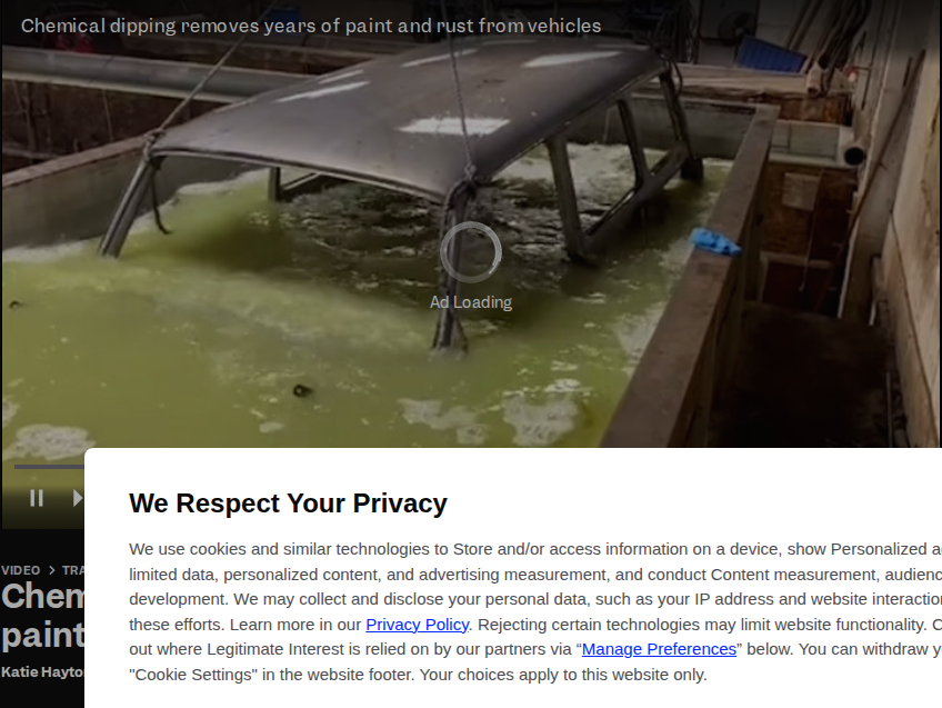 Bare vehicle frame submerged in a green chemical dipping tank, illustrating industrial-scale acid-bath automotive restoration