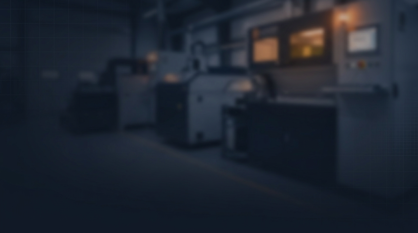 Blurred dark industrial facility interior with deep navy and charcoal tones, warm amber lighting accent in upper right suggesting active laser equipment.